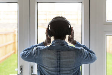 Woman with headphones looking through window - WPEF03877