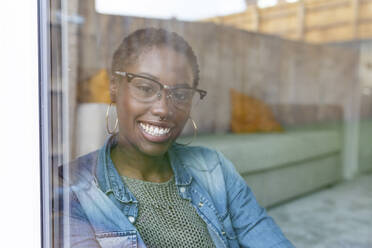 Lächelnde Frau schaut durch ein Fenster - WPEF03885
