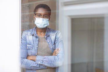 Portrait of woman in face mask seen through window - WPEF03894