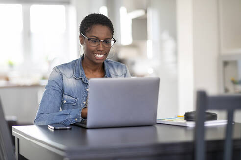 Lächelnde Frau arbeitet zu Hause am Laptop - WPEF03898