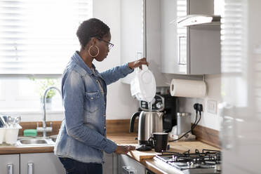 Frau gießt Wasser in einen Wasserkocher in der Küche - WPEF03911
