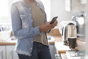 Frau benutzt Smartphone in der Küche - WPEF03912