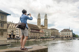 Schweiz, Zürich, Mann fotografiert Limmat und Altstadtgebäude - TAMF02737