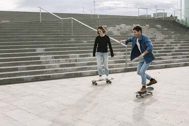 Young couple skateboarding walking near steps - XLGF00996