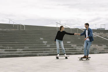 Young couple skateboarding walking near steps - XLGF00997