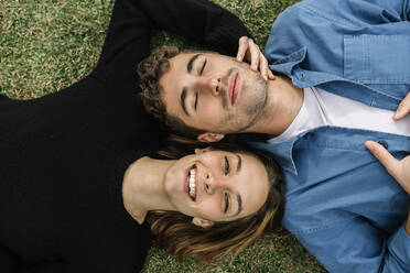 Lächelndes Paar auf dem Rasen liegend - XLGF01015