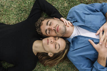 Smiling couple lying on lawn with eyes closed - XLGF01016