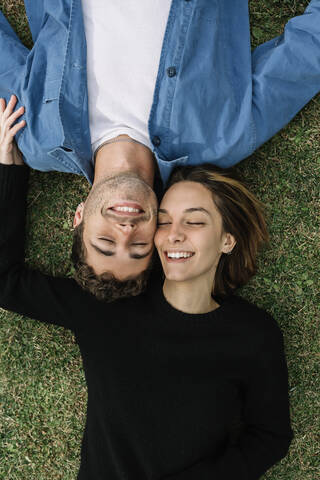 Smiling couple lying on lawn stock photo