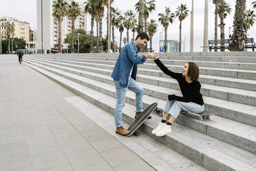 Couple with skateboards fist bumping outdoors - XLGF01027