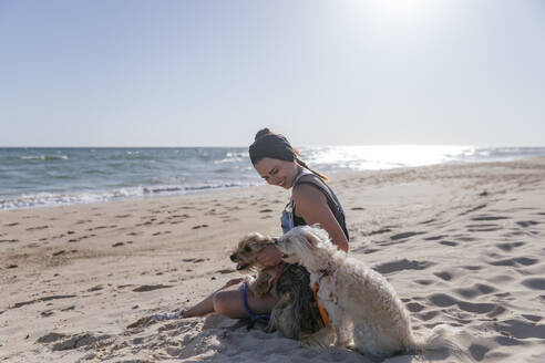 Frau spielt mit ihren Hunden am Strand - JRVF00091