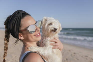 Frau hält ihren Hund am Strand - JRVF00093