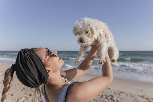 Frau hält ihren Hund am Strand - JRVF00094
