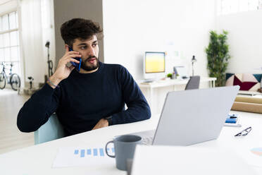 Young businessman talking on phone in creative office - GIOF10546