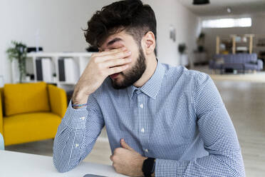 Tired businessman sitting in office - GIOF10572