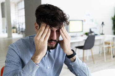 Müder Geschäftsmann sitzt im Büro - GIOF10573