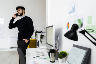 Geschäftsmann, der im Büro mit seinem Smartphone telefoniert - GIOF10602