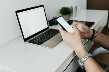 Man working on laptop and mobile phone at home - EBBF02121