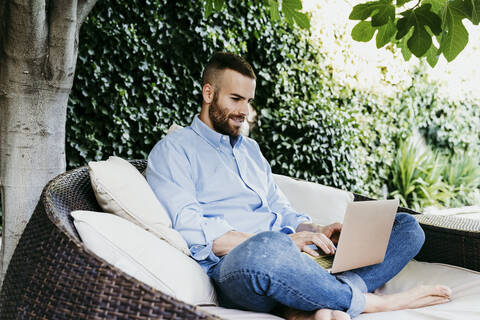 Young man working on laptop while sitting on terrace stock photo