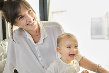 Portrait of mother and baby daughter sitting together and smiling - AODF00258