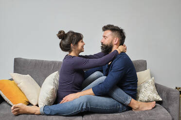 Erwachsenes Paar sitzt zusammen auf dem Sofa - AODF00270
