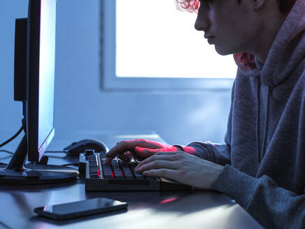 Mittelteil eines Teenagers, der Daten von einem Computer auf dem Schreibtisch abruft - ABRF00827