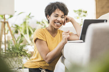 Smiling woman using digital tablet while sitting at home - UUF22623