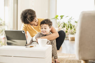 Mutter unterrichtet ihren Sohn mit Hilfe eines digitalen Tablets, während sie zu Hause sitzt - UUF22641