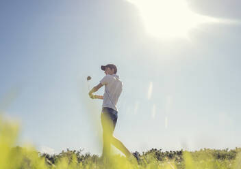 Jugendlicher spielt Golf gegen den klaren Himmel an einem sonnigen Tag - AJOF00981