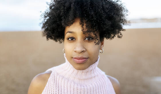 Nahaufnahme eines Porträts einer jungen Frau mit Afro-Haar am Strand - MGOF04643