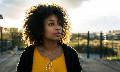 Nahaufnahme einer nachdenklichen schönen Frau mit Afro-Haar gegen den Himmel - MGOF04651