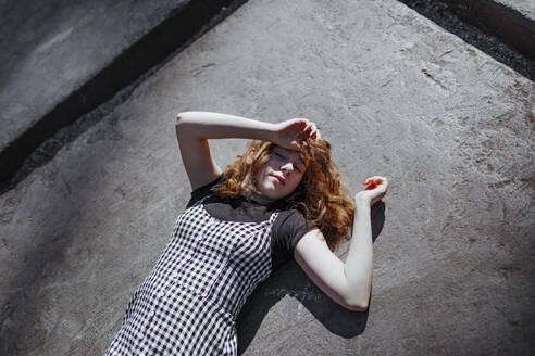 Teenage girl lying on footpath during sunny day - OGF00779