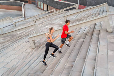 Von oben Seitenansicht von zwei Läufern in Sportkleidung, die auf einer Treppe joggen, während sie in der Stadt trainieren - ADSF19877