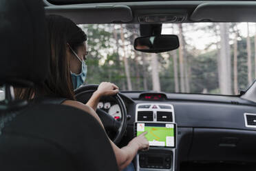 Frau mit Gesichtsmaske benutzt GPS beim Autofahren - EBBF02189