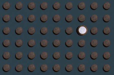 Muster aus Reihen von braunen Keksen mit einem einzigen mit weißer Spitze - KNTF06122
