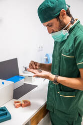 Side view of dentist holding gray dental plaster cast in dentistry laboratory - ADSF19937