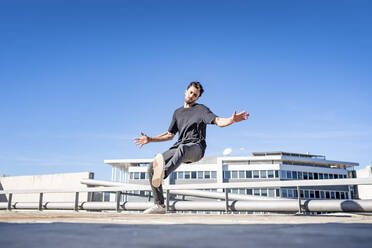 Junger Mann tanzt auf dem Dach stehend - GGGF00822