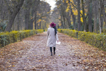 Mittlere erwachsene Frau mit Hut, die im Herbst auf einem Grundstück im Park spazieren geht - GGGF00839