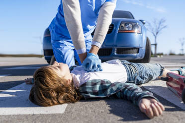 Rettungskräfte bei der Herz-Lungen-Wiederbelebung eines nach einem Autounfall auf der Straße liegenden Opfers - GGGF00859