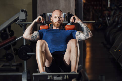 Man doing quadriceps exercise on hack squat machine at gym - MIMFF00405