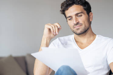 Man reading paper while working at home - SBOF02386