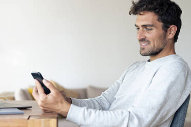 Man using mobile phone while sitting at home - SBOF02407