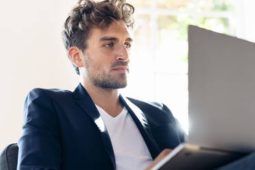 Businessman working on laptop while sitting at home - SBOF02423