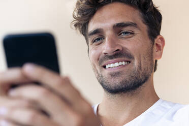 Mann lächelnd bei der Benutzung eines Mobiltelefons zu Hause - SBOF02441