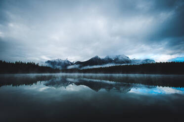 Eine stimmungsvolle Spiegelung der Berge im Banff National Park auf einem ruhigen See - CAVF91673