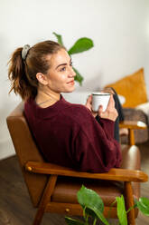 Frau lächelt und genießt Kaffee zu Hause - CAVF91723