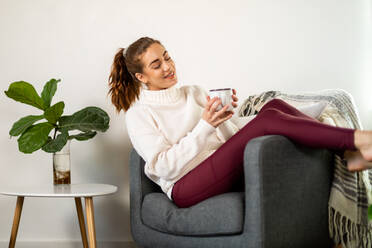 Woman Enjoys Coffee Reclining In Her Chair - CAVF91725