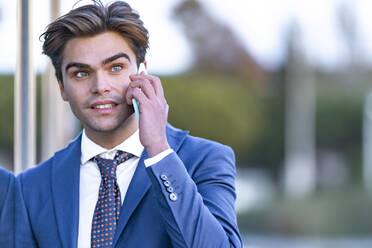 Male entrepreneur with gray eyes talking on mobile phone - GGGF00895