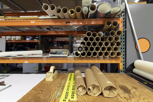 Paper rolls on workbench against rack in print shop - ISPF00044