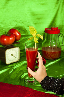 Frau hält Glas Tomatensaft mit Sellerieblatt - ERRF04887