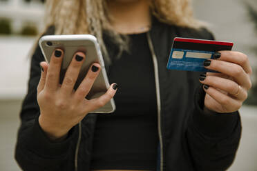 Junge Frau beim Einkaufen mit Smartphone und Kreditkarte - ACPF01028